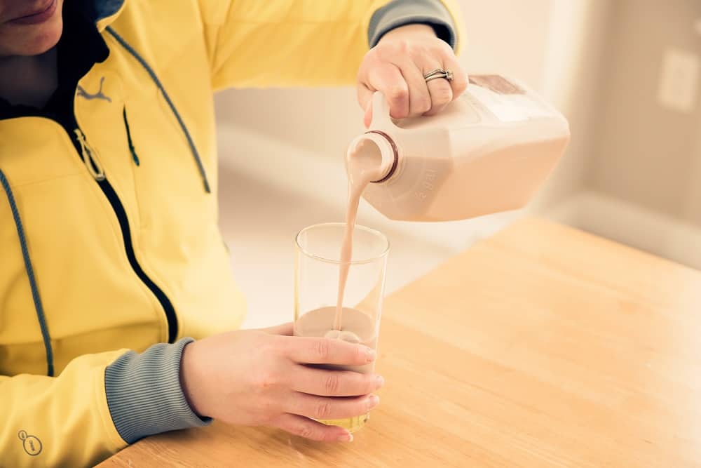 A woman pouring a glass of chocolate milk