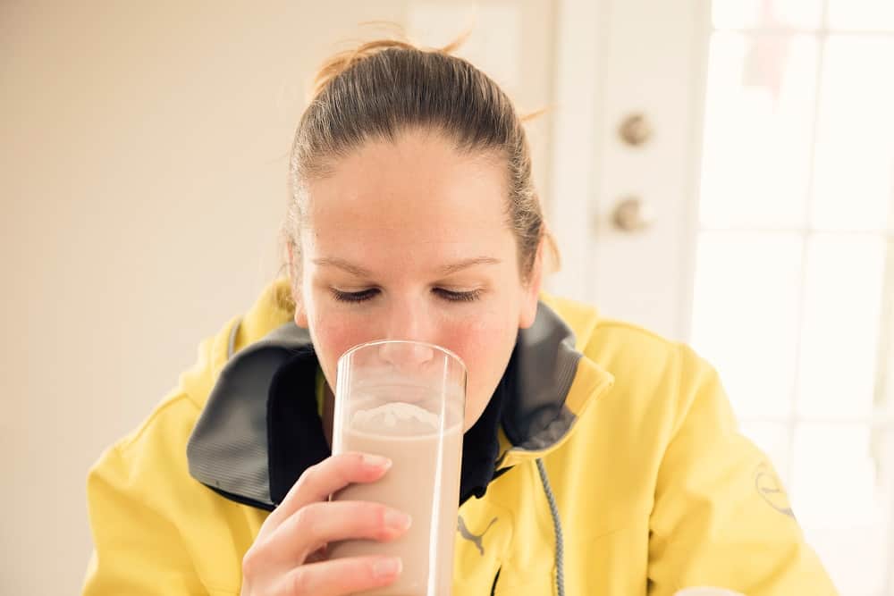 a woman drinking a glass of chocolate milk after a workout