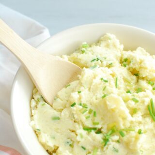 greek yogurt mashed potatoes in a bowl with a wooden spoon to scoop them