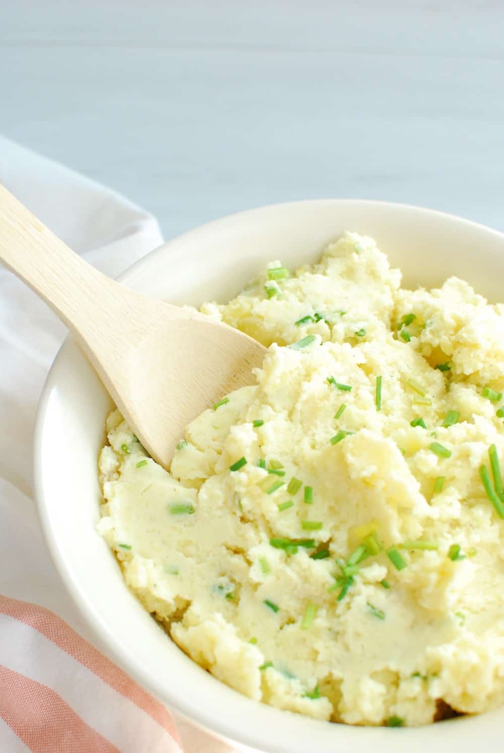 greek yogurt mashed potatoes in a bowl with a wooden spoon to scoop them