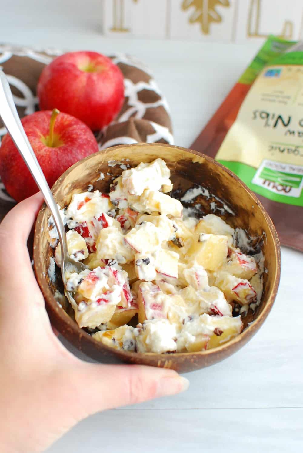 A brown bowl full of caramel apple salad with a spoon in it