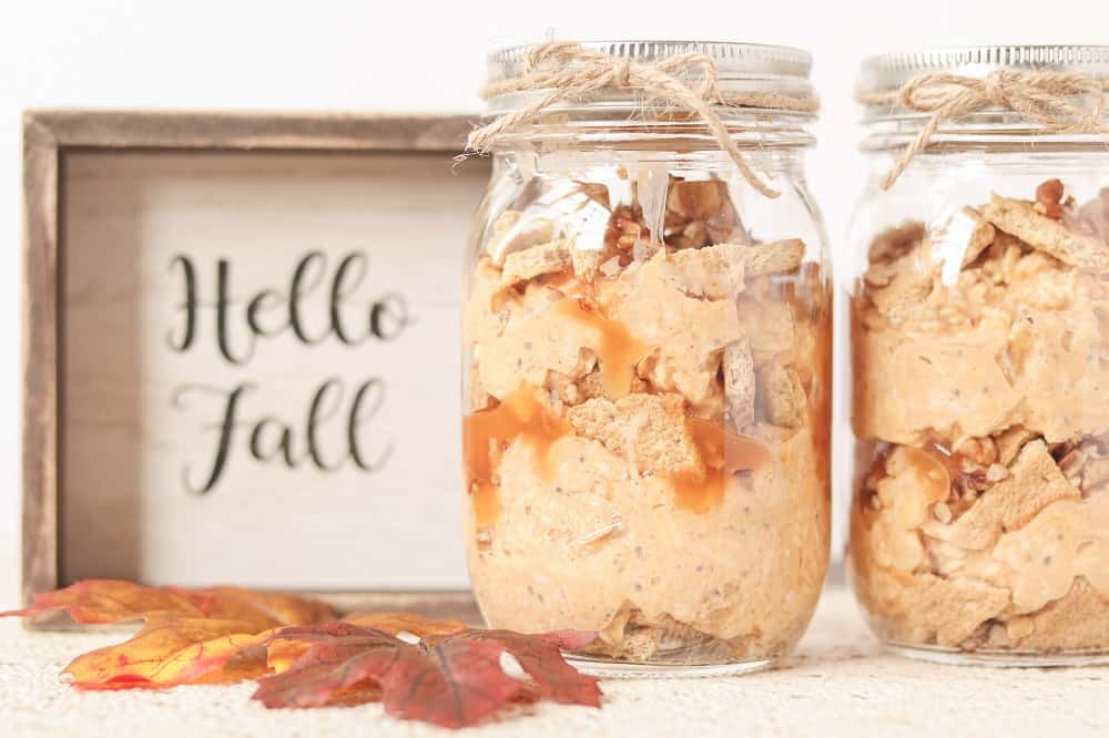 two mason jars of pumpkin overnight oats next to a sign that says hello fall