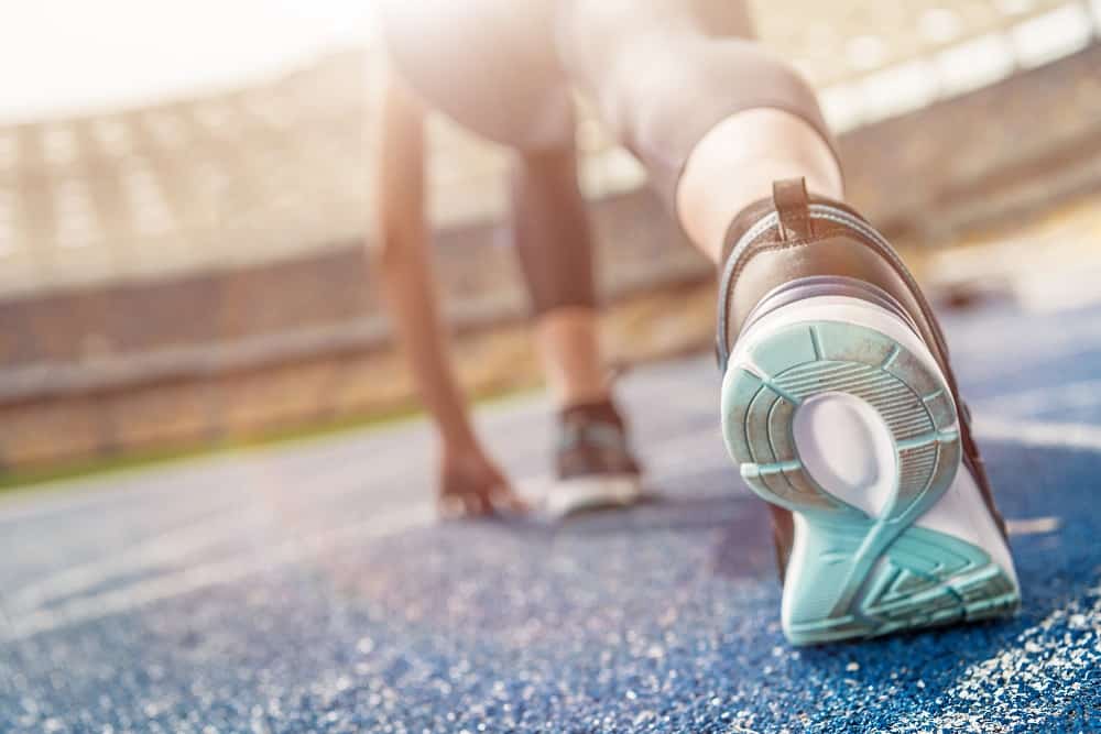 A close up of a woman's shoe as she gets ready to run 2 miles on a track