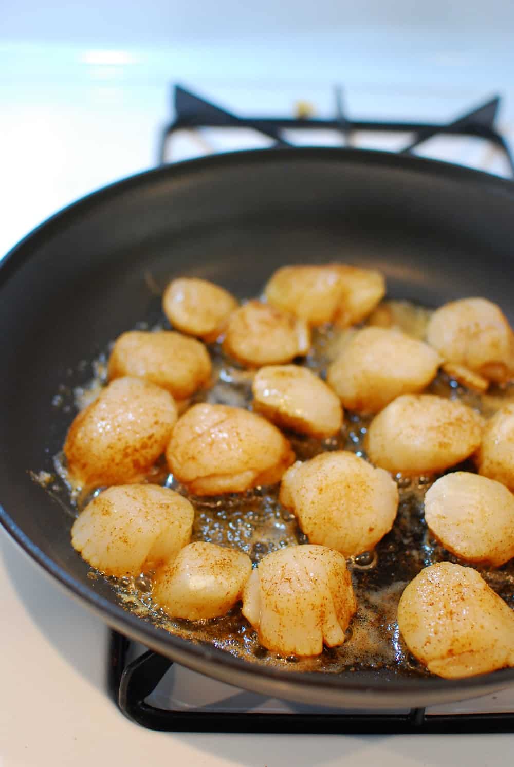 scallops cooking in a pan with butter