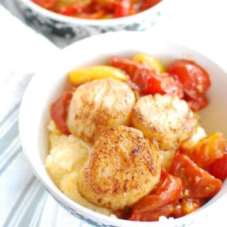A bowl full of scallops and grits along with balsamic cherry tomatoes
