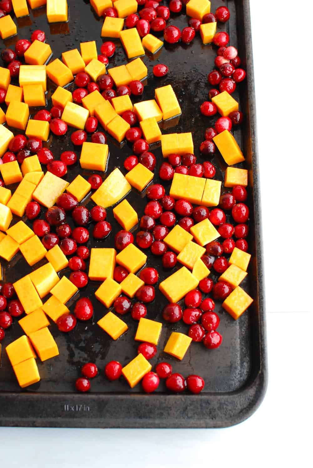 butternut squash and cranberries on a baking sheet prior to cooking