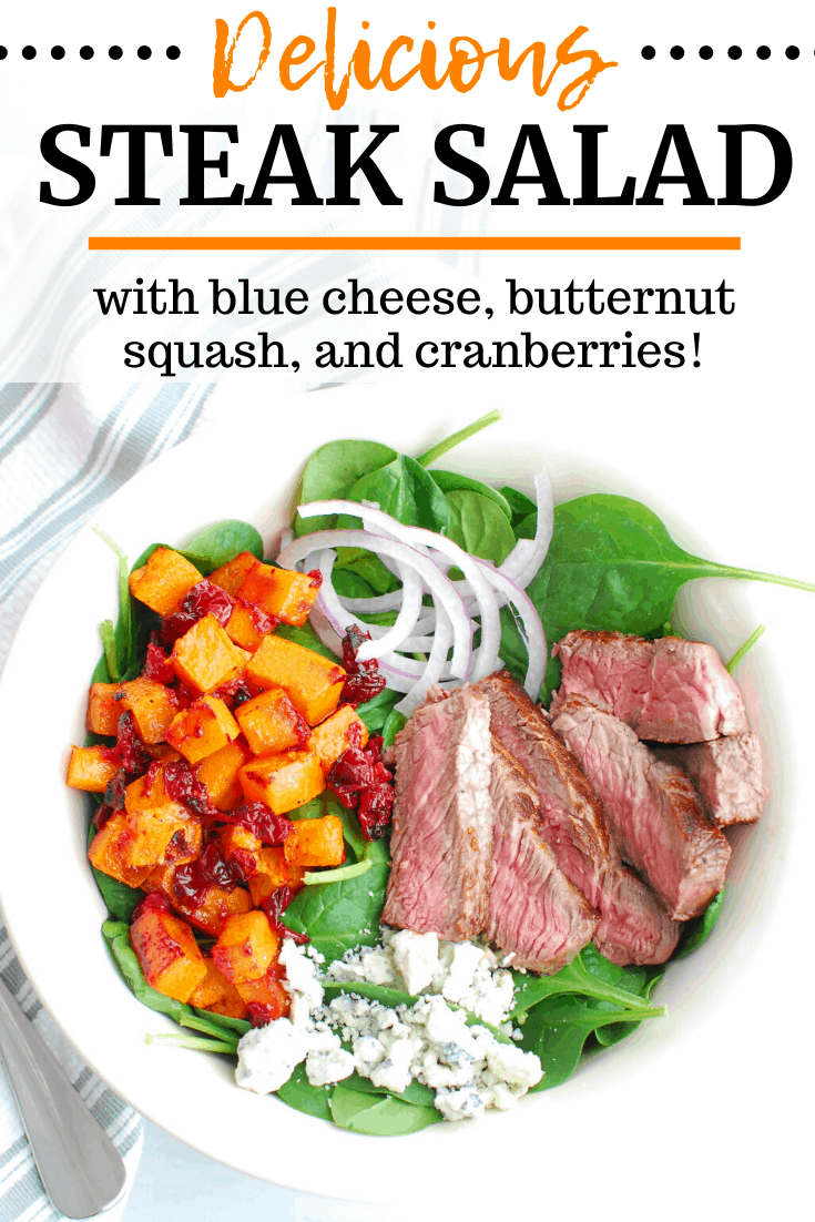 A steak salad with blue cheese, butternuts squash, cranberries, and spinach in a white bowl