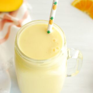 mango pineapple post run smoothie in a mason jar with a straw
