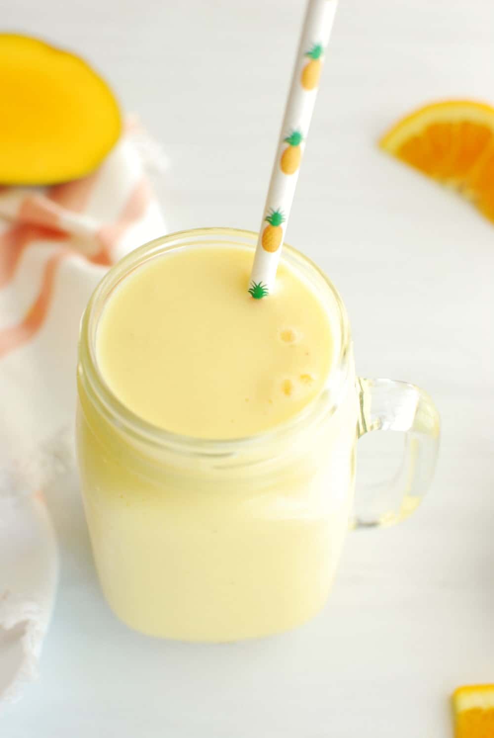 mango pineapple post run smoothie in a mason jar with a straw