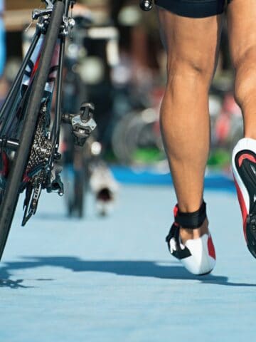 A man running his bike in during the transition in a half ironman race.