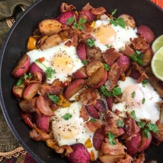 Healthy breakfast skillet meal with eggs, veggies, and bacon in a cast iron pan