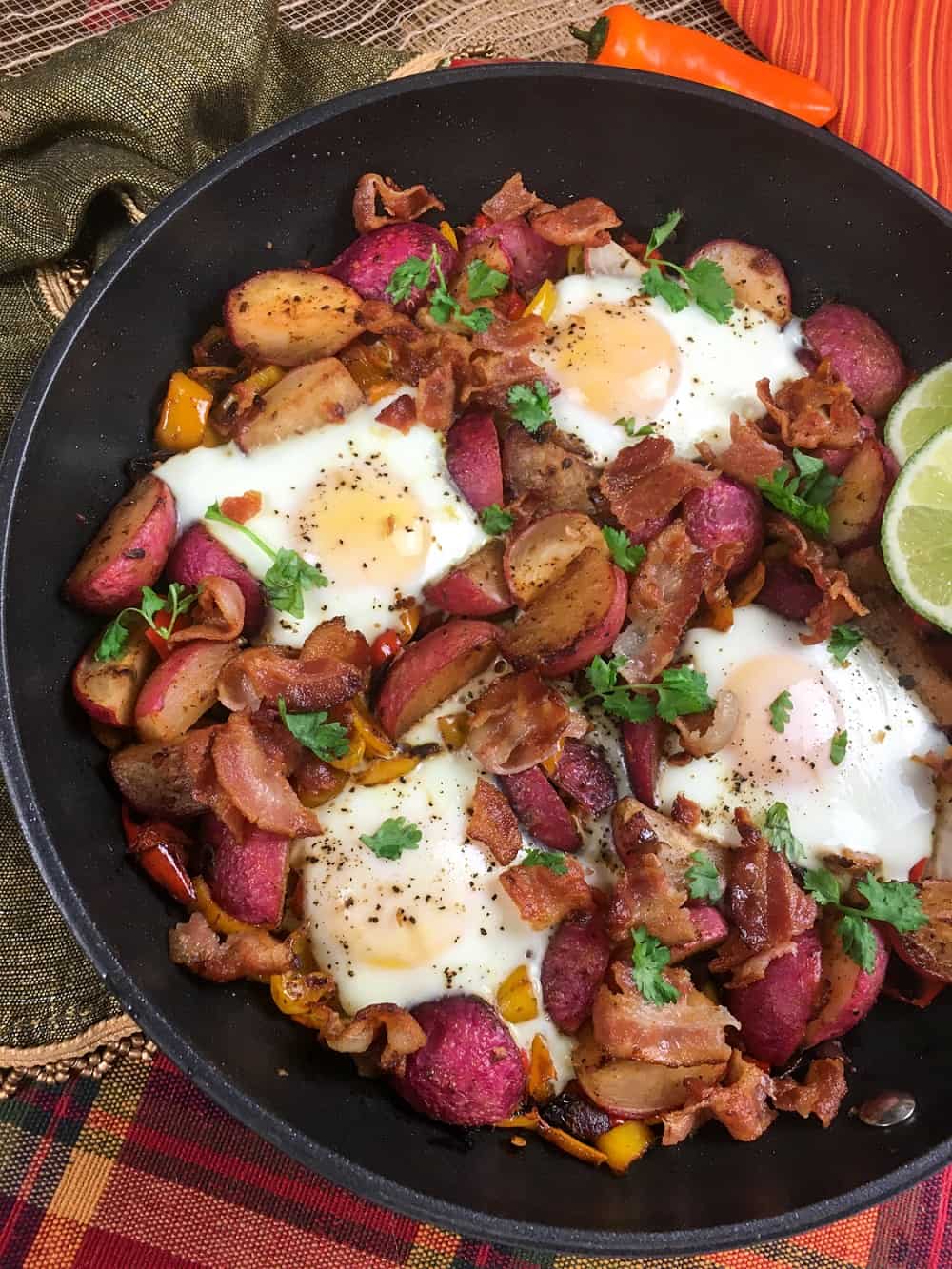 Healthy breakfast skillet meal with eggs, veggies, and bacon in a cast iron pan