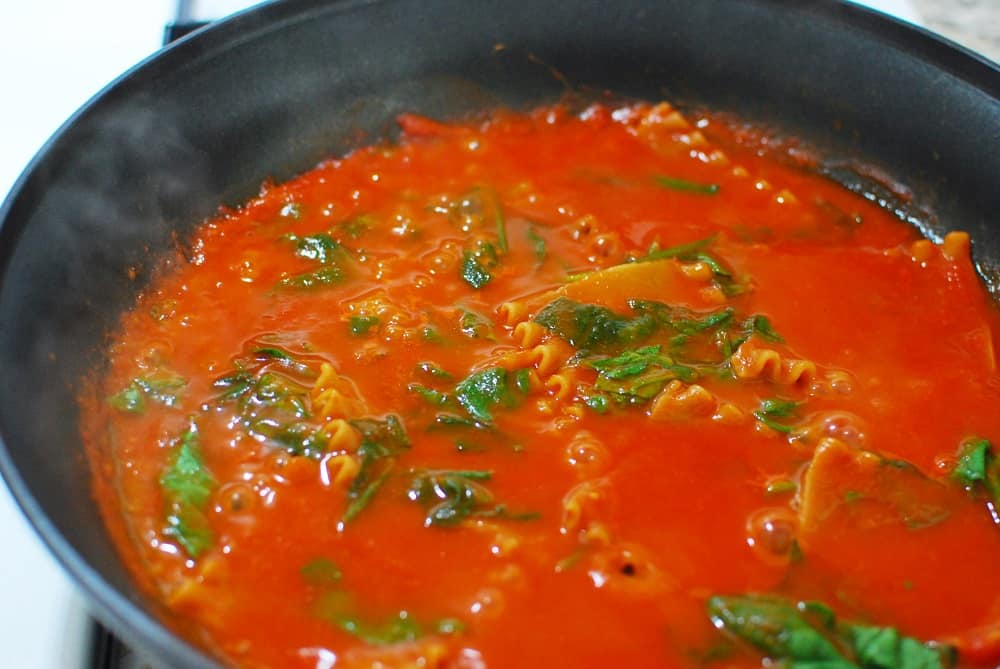 lasagna noodles and pasta sauce cooking in a skillet