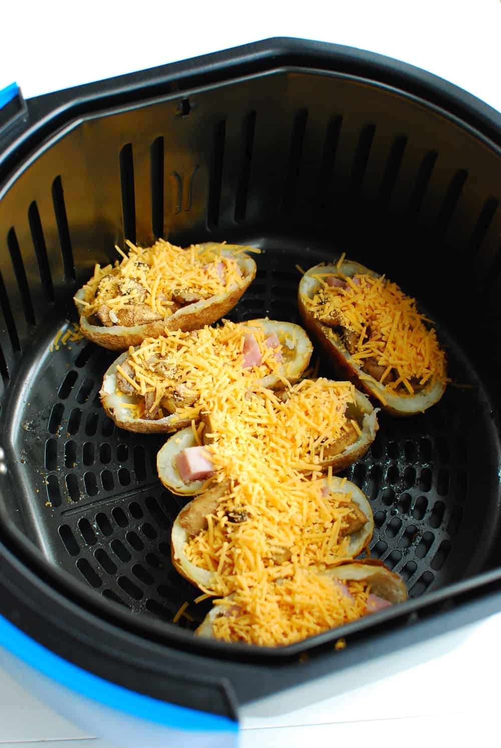 Potato skins topped with extra cheese in an air fryer basket