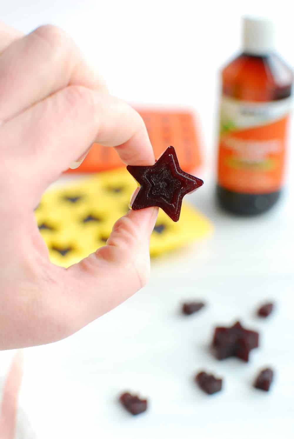 a woman holding a star shaped elderberry gummy