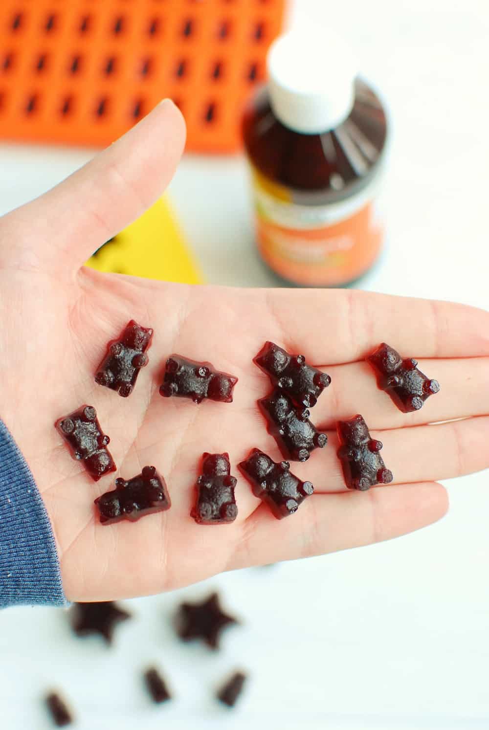 A bunch of homemade elderberry gummy bears in a woman's hand.