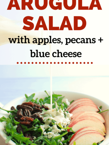 an apple arugula salad with dressing being drizzled on top