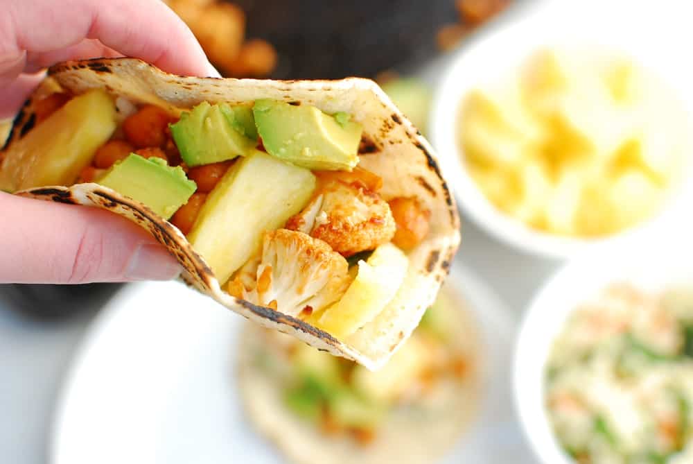 a woman holding a bbq cauliflower taco