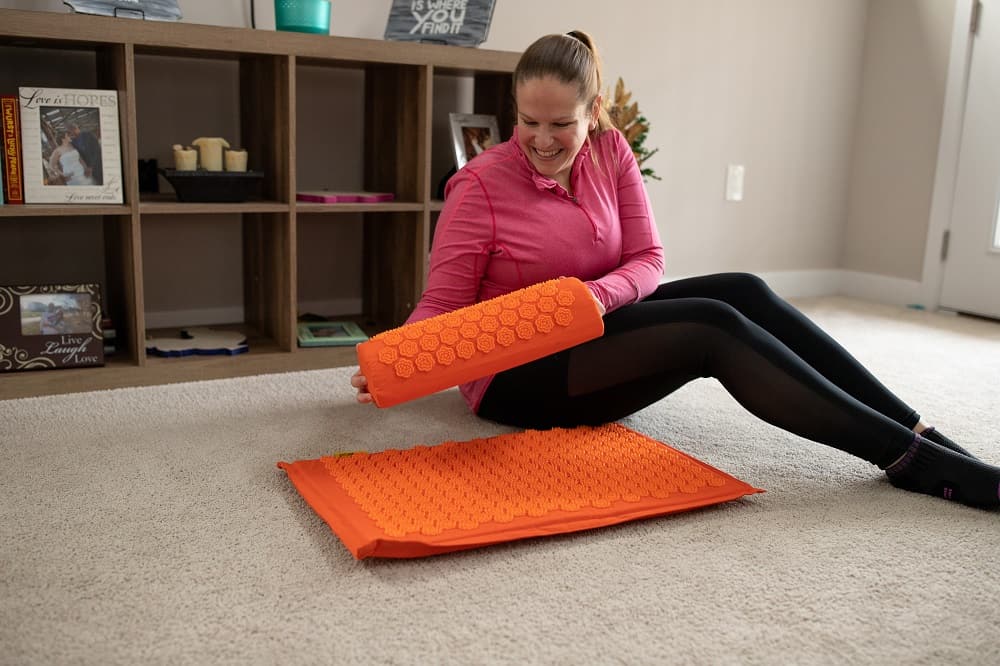 A woman holding an acupressure mat