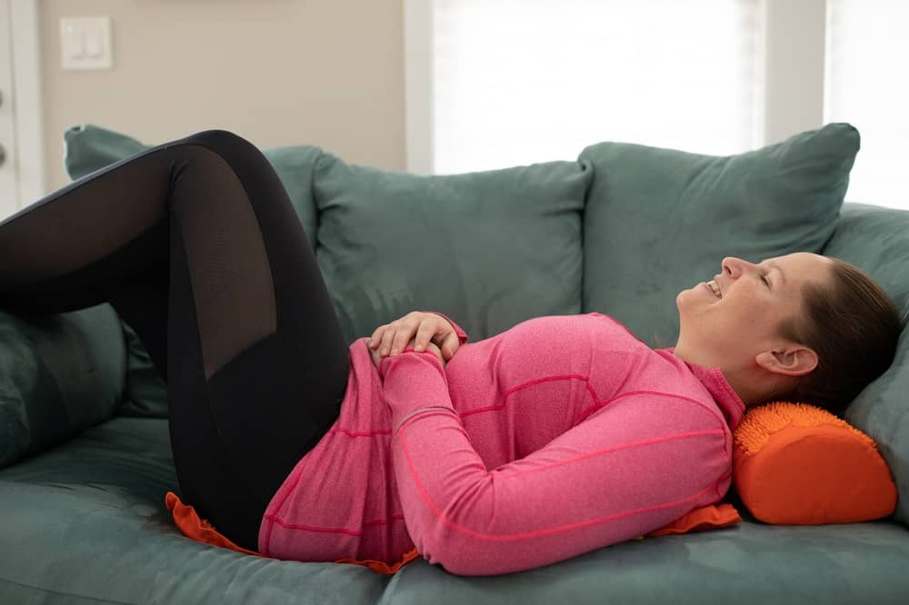 a woman using an acupressure mat on a couch