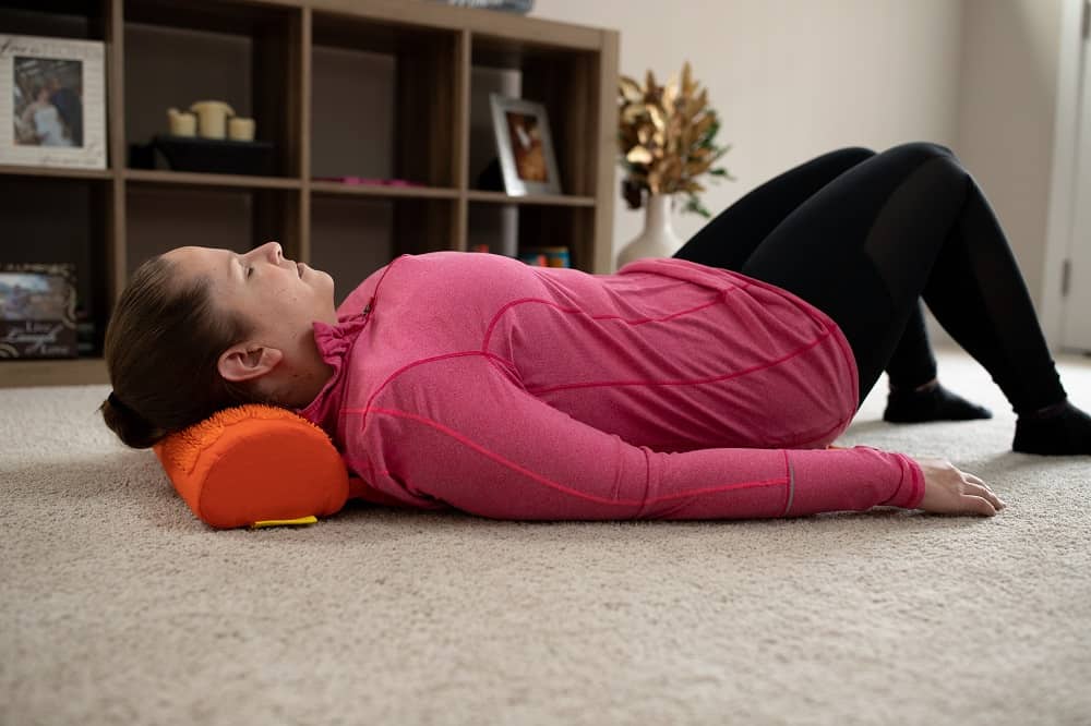 a woman laying on an orange acupressure mat on the ground