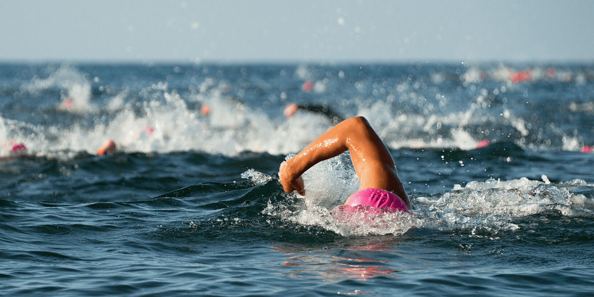 a woman swimming with a swim cap on in the ocean
