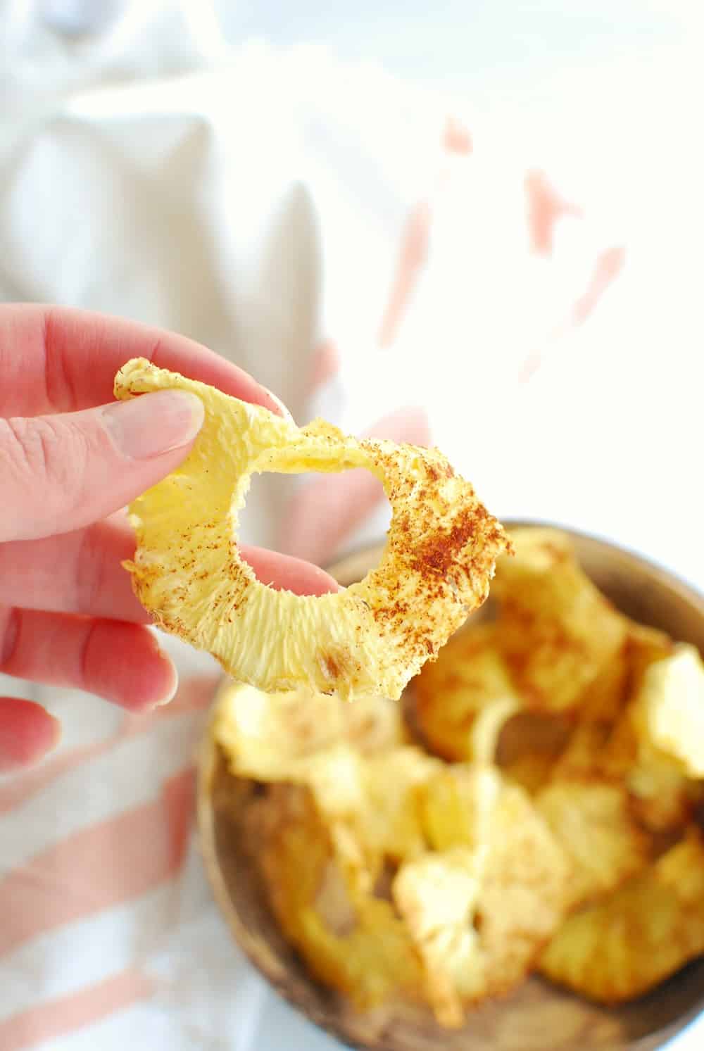 a woman holding dried pineapple in her hand