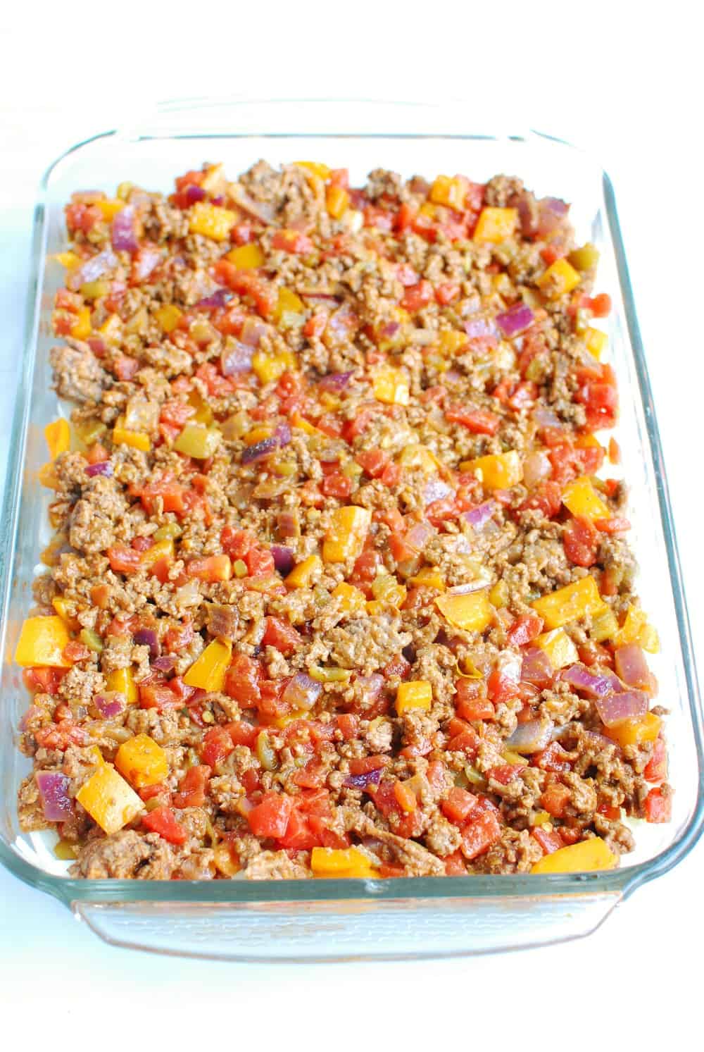 a casserole dish filled with hashbrown potatoes then topped with a ground beef mixture