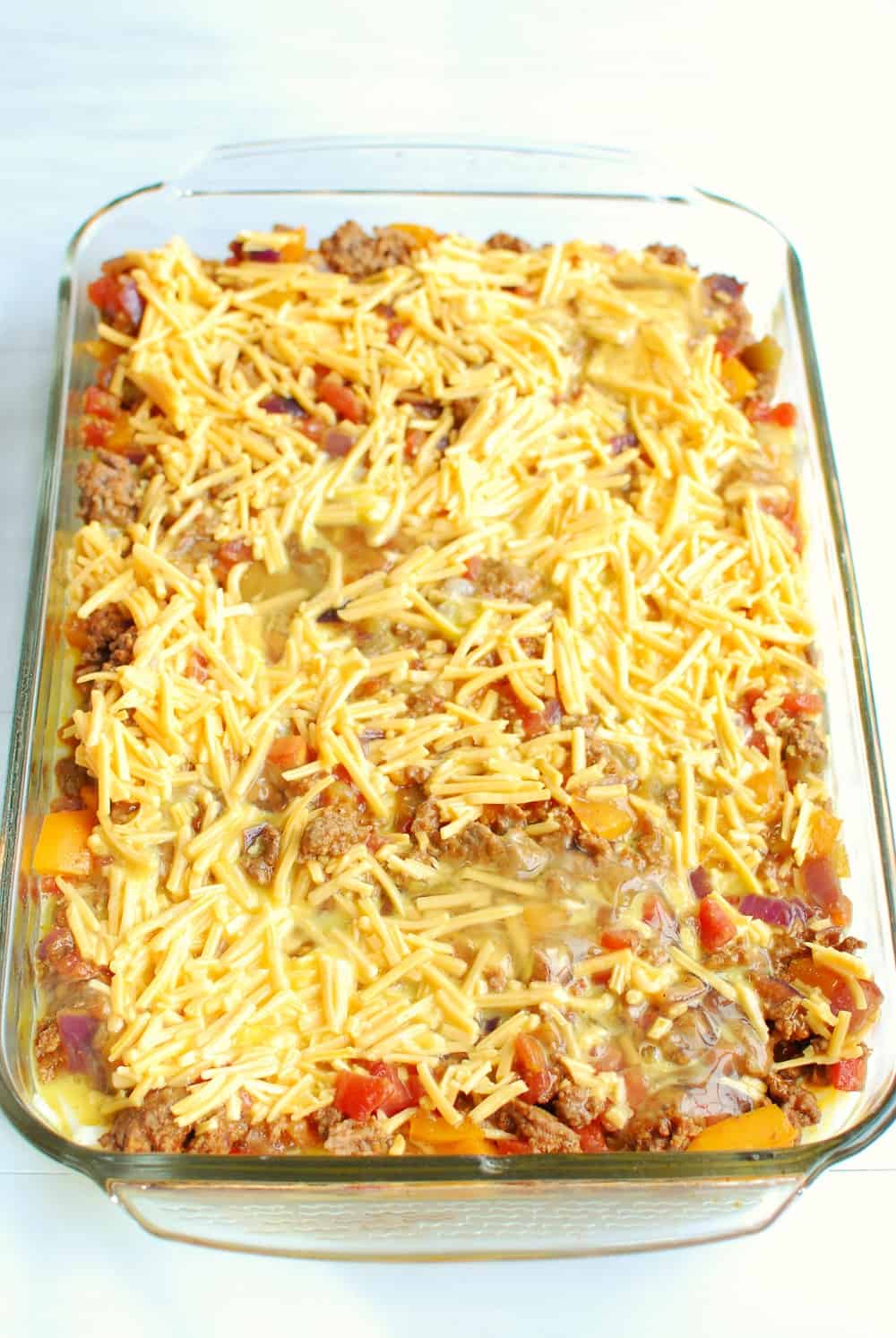 adding the last layer of the casserole, the eggs and cheese, to the casserole dish