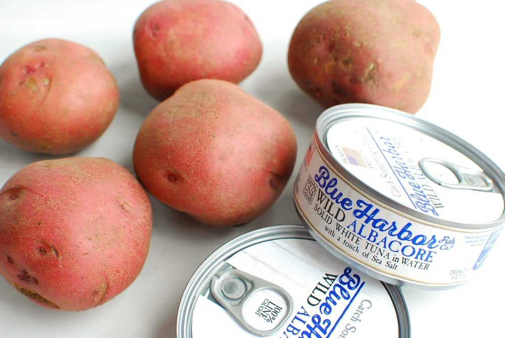 several cans of tuna next to some red potatoes