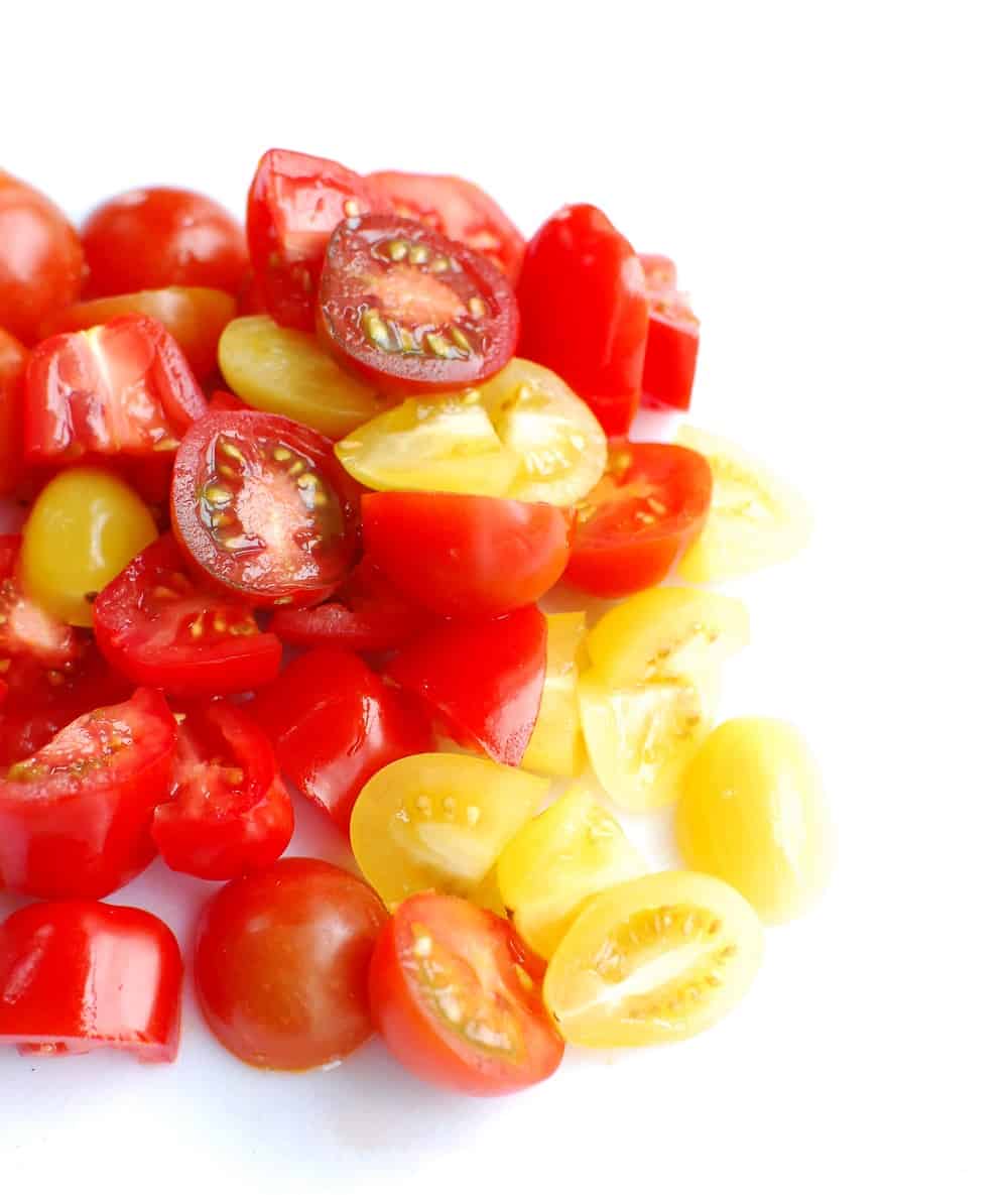 chopped cherry tomatoes on a white cutting board