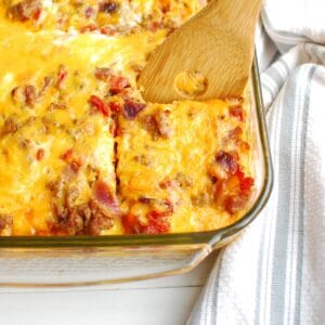 A wooden spatula taking out a piece of taco breakfast casserole from the casserole dish.