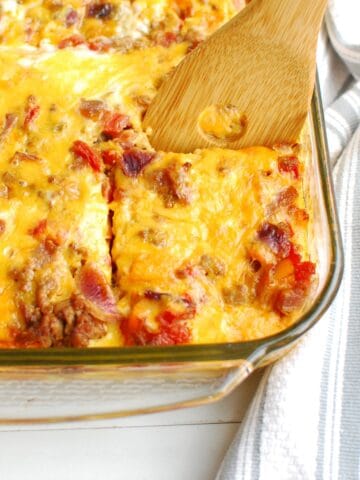 A wooden spatula taking out a piece of taco breakfast casserole from the casserole dish.