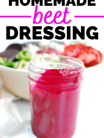 a small jar filled with beet dressing, next to a bowl of salad