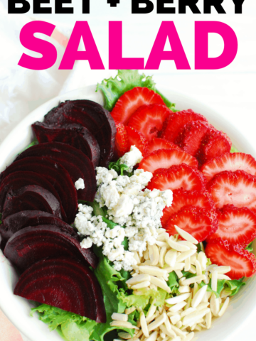 a strawberry beet salad in a large white bowl next to a cloth napkin