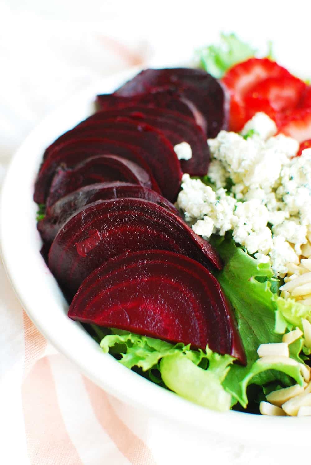 sliced beets on top of green leaf lettuce 