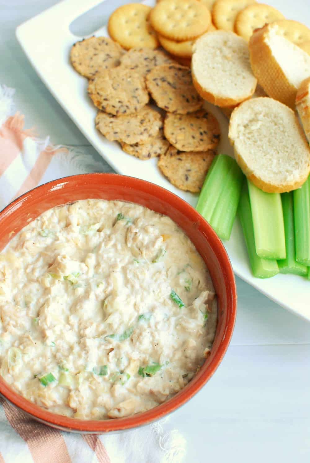 a ramekin full of hot salmon dip, next to dippers like celery and baguettes