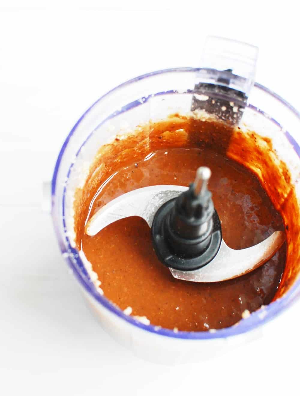 a food processor bowl with the finished chocolate coconut macadamia butter