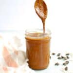 A jar of chocolate macadamia nut butter with a spoon dunked into it.