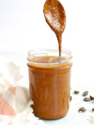 A jar of chocolate macadamia nut butter with a spoon dunked into it.