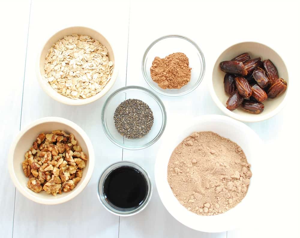 bowls of walnuts, chia seeds, oats, cold brew coffee, cocoa powder, protein powder, and dates