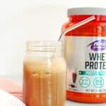 a mason jar with protein coffee next to a container of protein powder