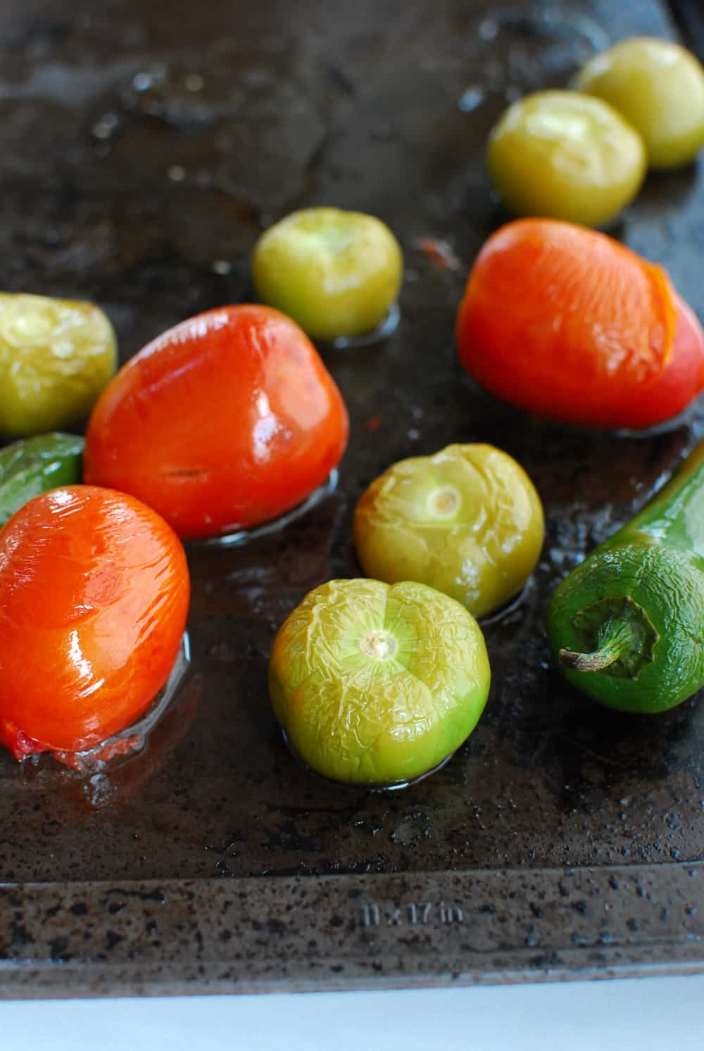 roasted tomatillos, tomatoes, and jalapenos on a baking sheet