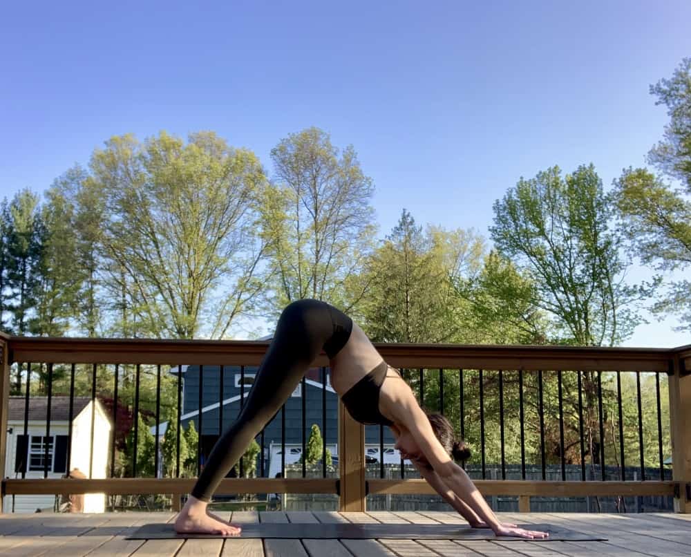 a woman doing downward dog yoga pose outside