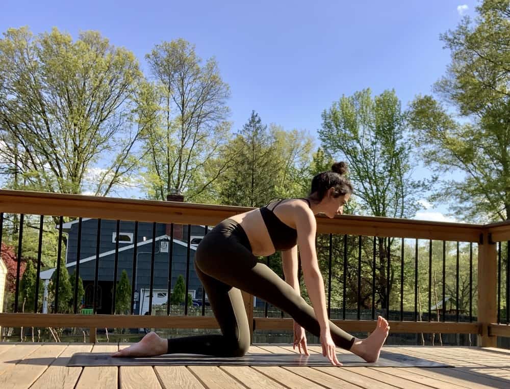 a woman doing a runners lunge yoga post outdoors on a deck