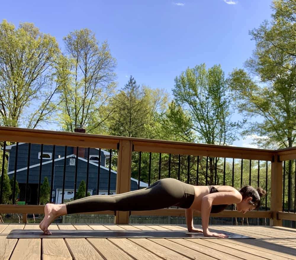 a woman doing a yoga push up pose outdoors on a deck
