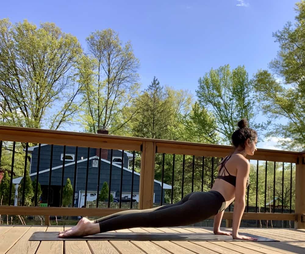 a woman doing an updog yoga pose outdoors on a deck