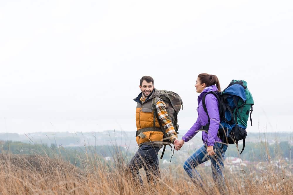 a couple taking a hike together outdoors with hiking backpacks