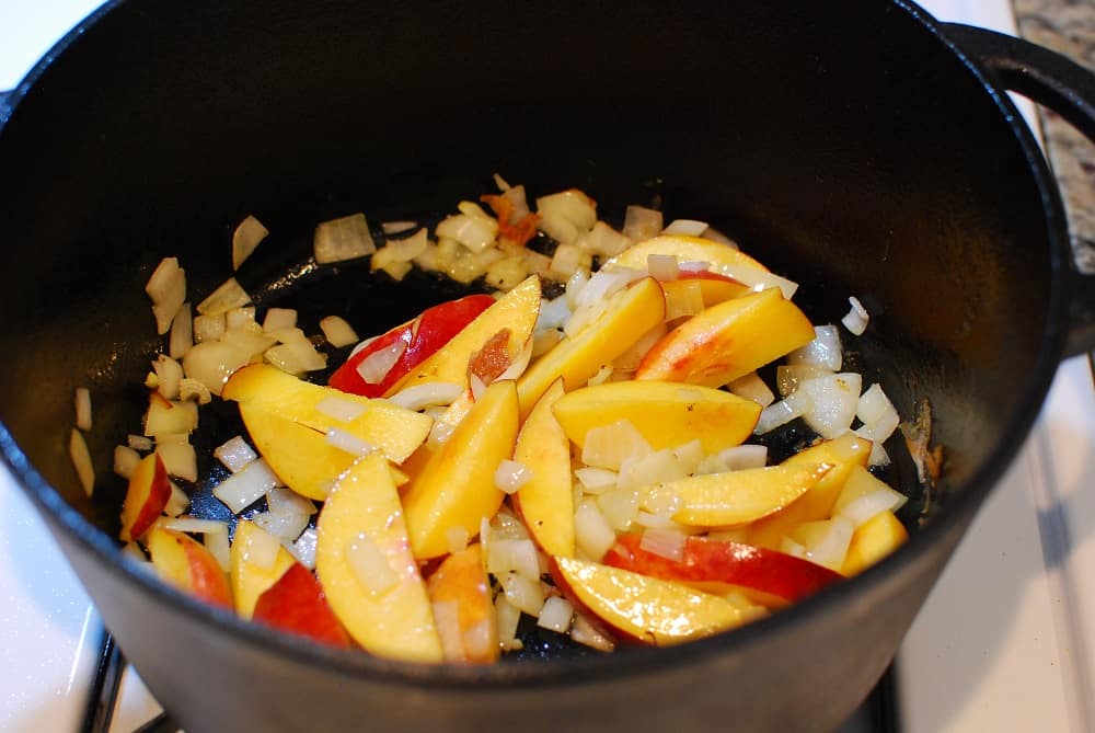 onions and peaches sauteing in a dutch oven