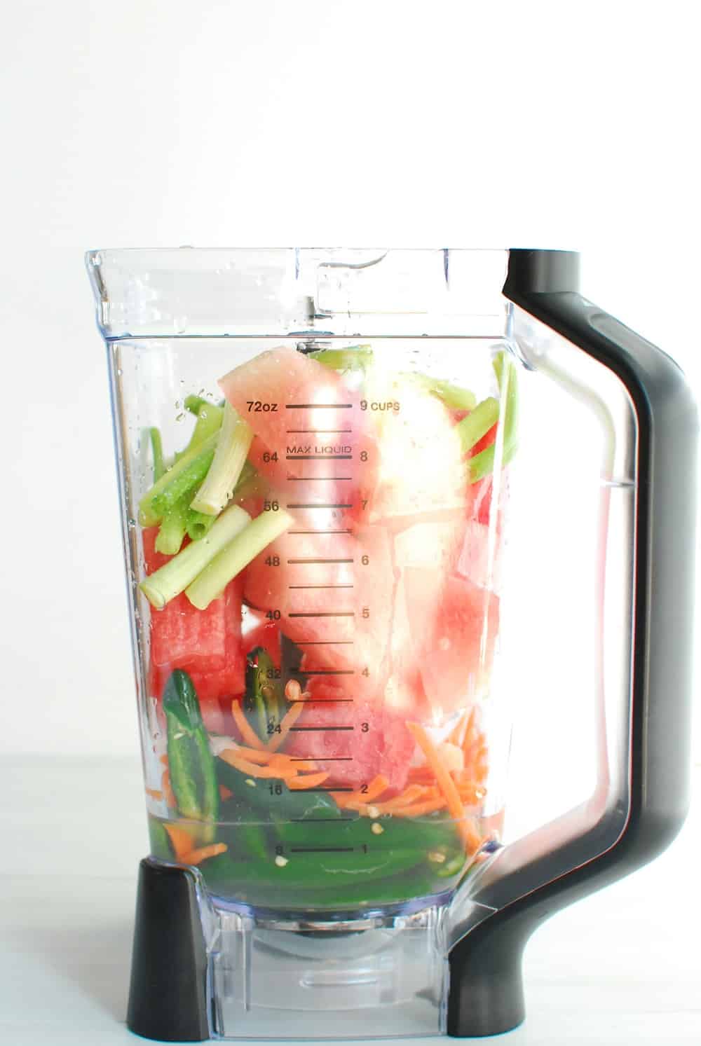 a blender full of watermelon, peppers, scallions, and other ingredients to make hot sauce